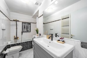Ein modernes Badezimmer mit Badewanne, Toilette und großem Spiegel.