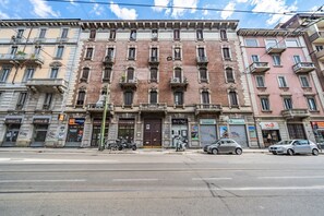 A multi-story building with a central entrance, several windows, and a street in front.