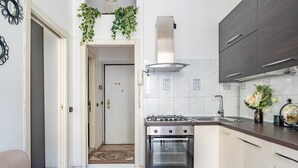 Une cuisine de taille réduite, équipée d’une cuisinière à gaz, d’un four et de meubles de rangement de couleur sombre.
