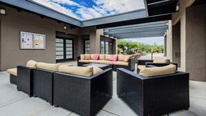 Un patio exterior con un área de estar techada, un tablón de anuncios y vistas al cielo.
