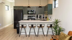 A modern kitchen with a central island, bar stools, and a ceiling fan. - Elderberry Farms Estate Farmstay (Traverse City)