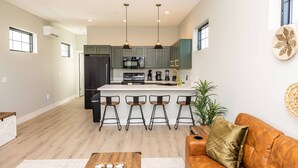 A modern kitchen with a central island, bar stools, and pendant lighting. - Elderberry Farms Estate Farmstay (Traverse City)