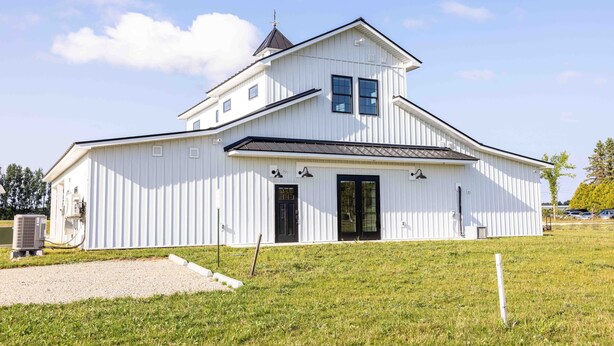 A white building with a gabled roof, two black doors, and a small tower-like structure on the roof. - Elderberry Farms Estate Farmstay (Traverse City)