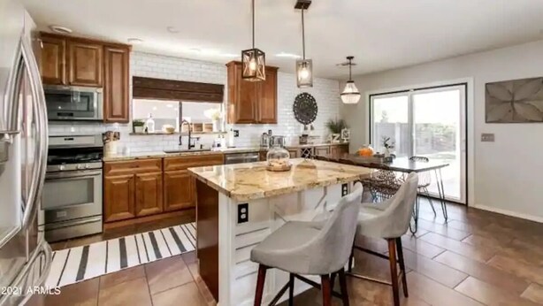 A modern kitchen with wooden cabinets, stainless steel appliances, a marble island, and pendant lighting. - Stunning Heated Pool +Game Room +Great Location
 (Gilbert)