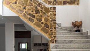 Un escalier en pierre mène à un palier d’où l’on a vue sur une partie de la cuisine.