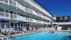 Ett poolområde på hotellet med flera nivåer av balkonger, solstolar och parasoller.