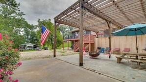 Ein überdachter Patio-Bereich mit einer Holzhütte, Picknicktischen und Gartenmöbeln.