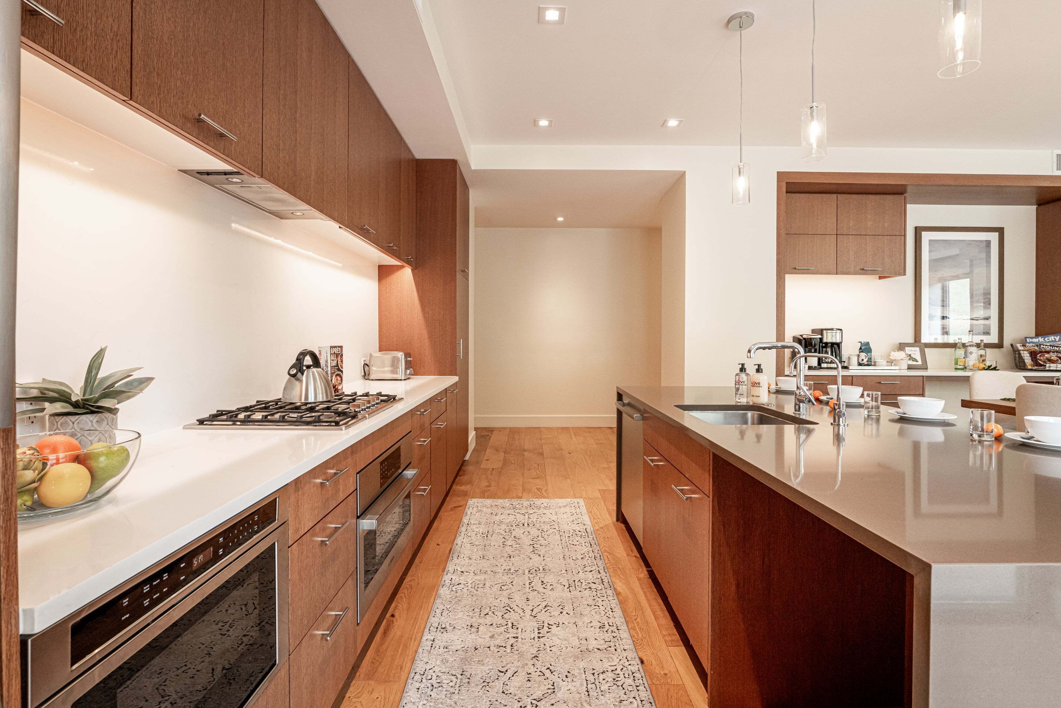 A modern kitchen with wooden cabinets, stainless steel appliances, and a large island with a sink.