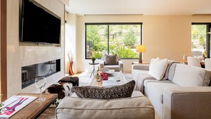 A modern living room with a flat-screen TV, a fireplace, a sofa, a coffee table, and a view of the outdoors. - Unbeatable Location! Near Hiking Trails! Park City Lift 301 Ski-in/Ski-out (Park City)