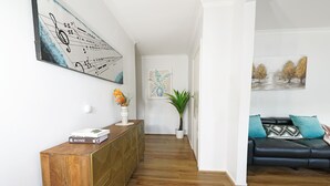 Un salon moderne avec un canapé en cuir noir, une console en bois et un grand tableau abstrait accroché au mur.