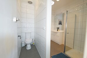 A bathroom with a toilet, sink, and shower area.