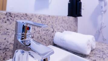 A bathroom with a chrome faucet, a white sink, a towel, and a towel rack.
