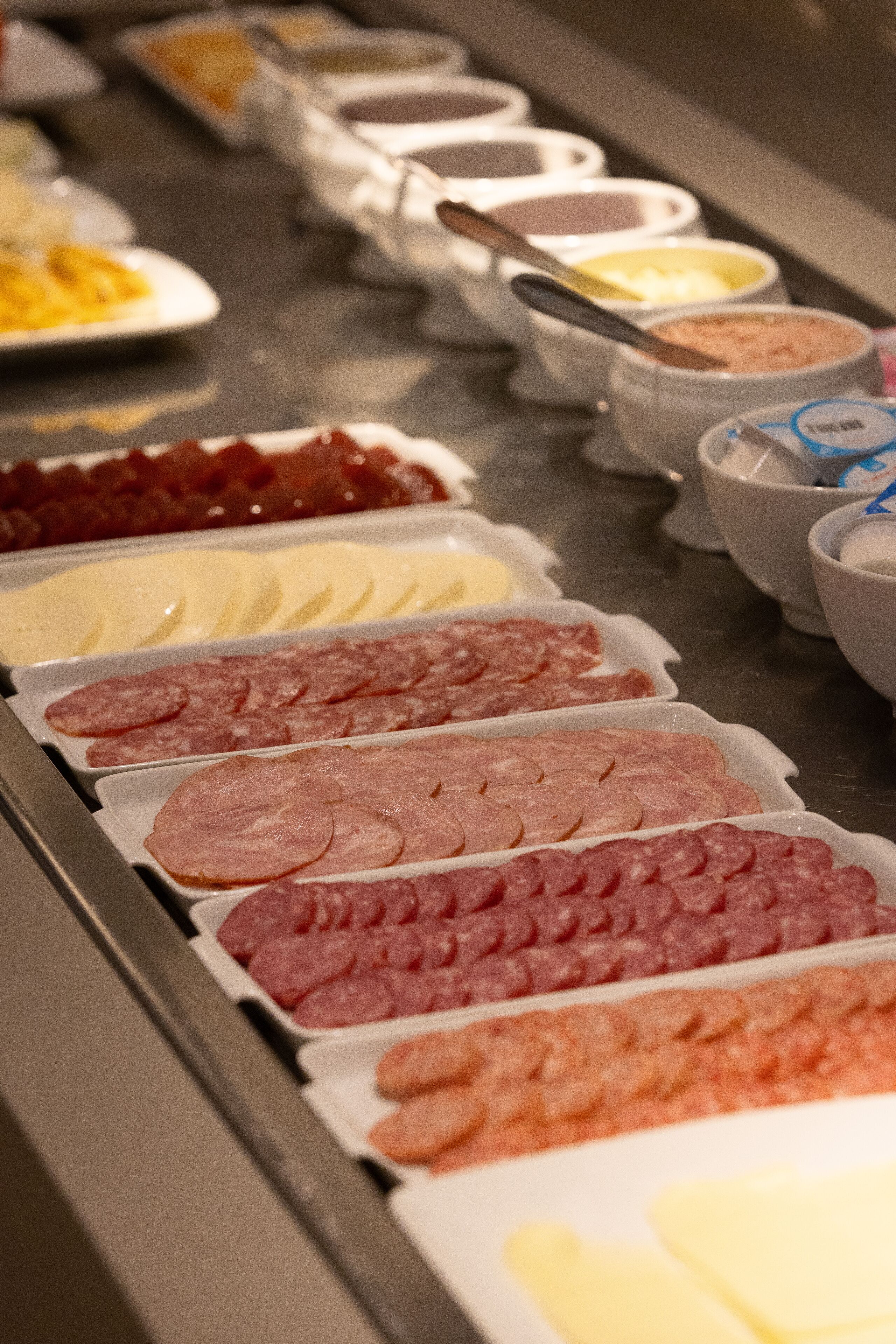 Un bufé con una variedad de alimentos, incluyendo fiambres y quesos.
