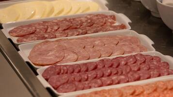 Un bufé con una variedad de alimentos, incluyendo fiambres y quesos.