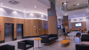 Een moderne lobby met een hoge plafond, een glazen balustrade en een receptiebalie.
