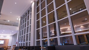 Een ruime lobby met grote ramen, moderne zitplaatsen en een hoge plafond.