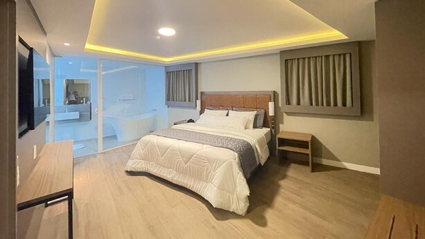 Een moderne slaapkamer met een groot bed, nachtkastjes en uitzicht op een badkamer.