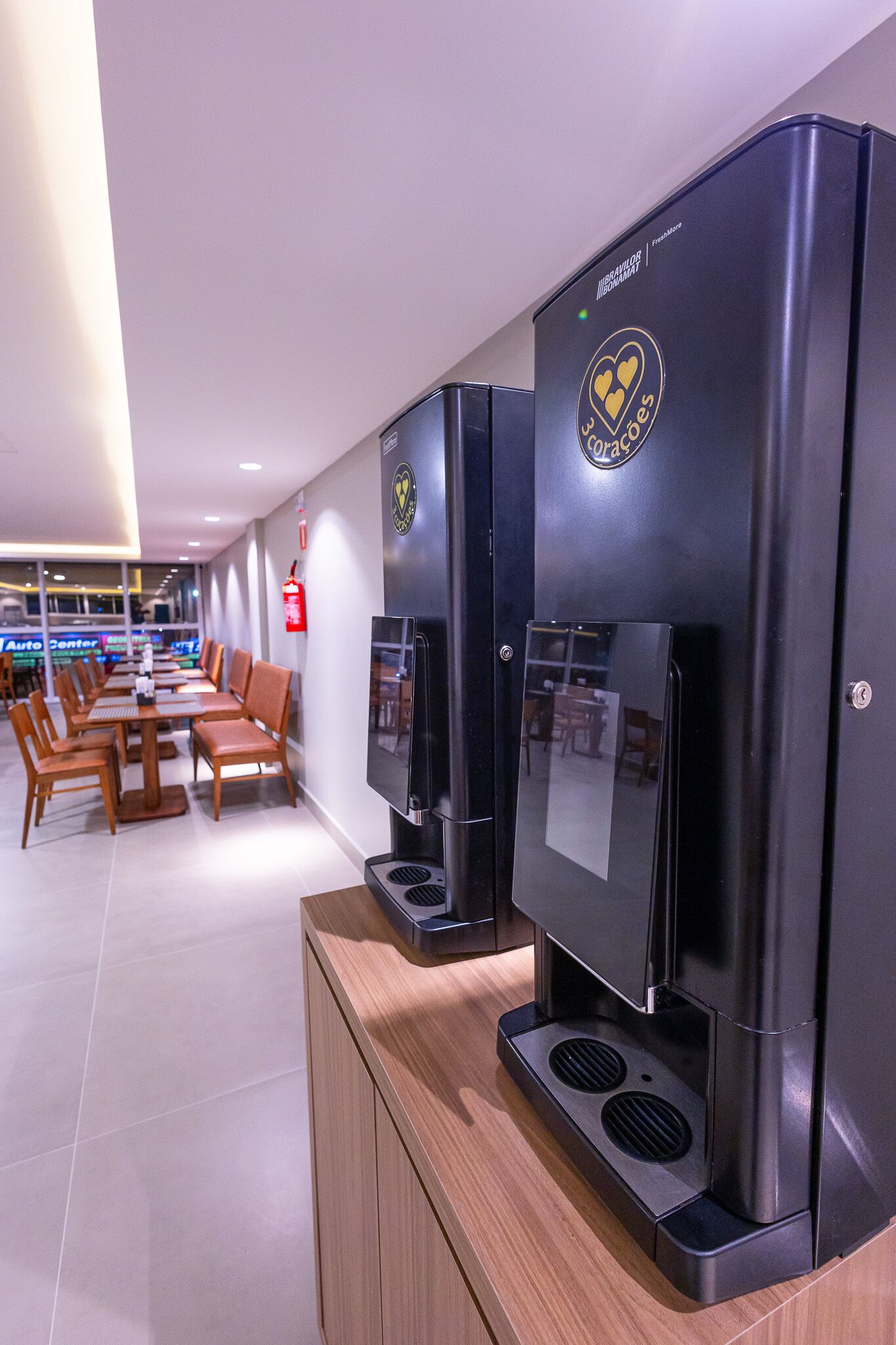 Un restaurante moderno con máquinas de café espresso, mesas y sillas de madera.