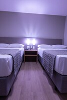 Habitación doble con dos camas, una mesita de noche y una lámpara de pared.