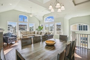 Relax in a spacious living area with expansive views of the surrounding neighborhood, featuring a comfortable L-shaped sofa set and a variety of seating options.