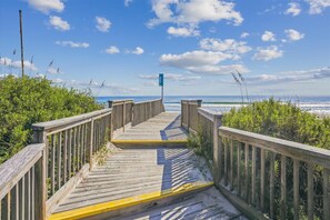 Walk along the boardwalk to the beach, surrounded by lush greenery and ocean views.