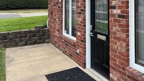 Una casa de ladrillo con puerta principal negra, una ventana pequeña y un buzón.