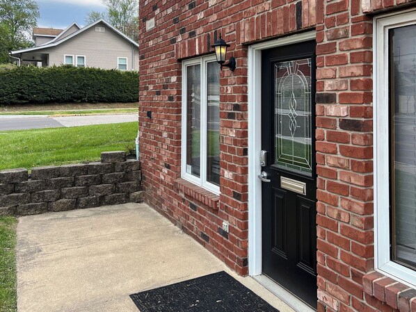 A brick house with a black front door, a small window, and a mailbox.