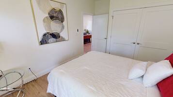 Un dormitorio con cama, armario y un cuadro en la pared.