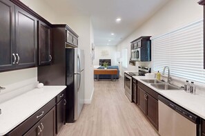 A modern kitchen with dark cabinets, stainless steel appliances, and a central island.
