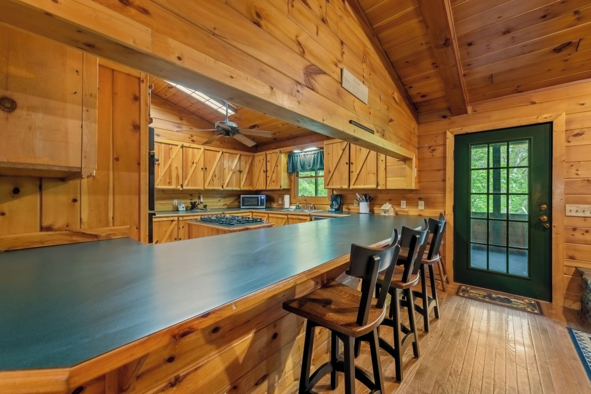 A wooden cabin interior with a kitchen area, bar counter, and seating.