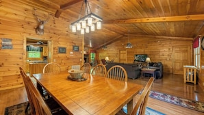L’intérieur d’un chalet en bois comprend une table à manger, des chaises, un canapé et un téléviseur.