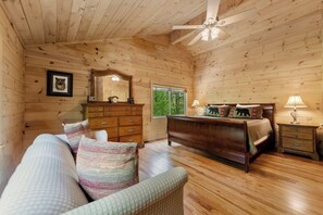 A wooden cabin bedroom with a bed, dresser, and a large mirror.