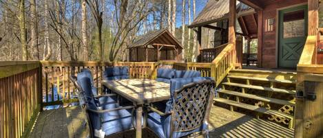 Eine Holzterrasse mit Tisch und Stühlen, umgeben von Bäumen.
