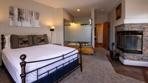 A bedroom with a large bed, a stone fireplace, a mirror, and a painting on the wall. - Eolus Ski-in/Ski-Out Condo w/ private hot tub/deck and Awesome Mountain Views (Durango)