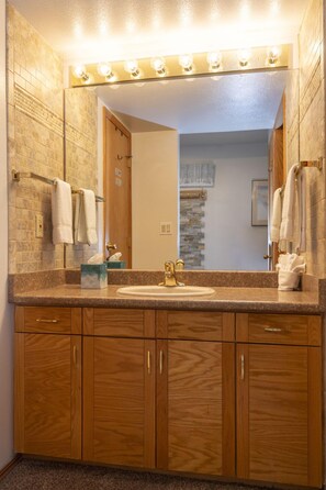 Une salle de bain avec un meuble-lavabo en bois, un évier et un grand miroir avec éclairage.