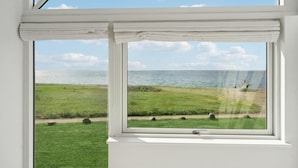 A window with a view of a grassy field and a body of water. - Nice home in Assens with house sea view (Assens)