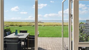 A patio with a table and chairs, a grassy area, and a view of the sea. - Nice home in Assens with house sea view (Assens)