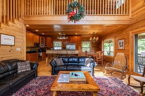 A cozy cabin interior with a living room, kitchen, and dining area.