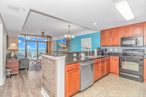 A modern kitchen with wooden cabinets, stainless steel appliances, and a view to the outside.