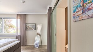 Une chambre à coucher avec un lit, un grand miroir, une fenêtre avec des rideaux et une carte accrochée au mur.