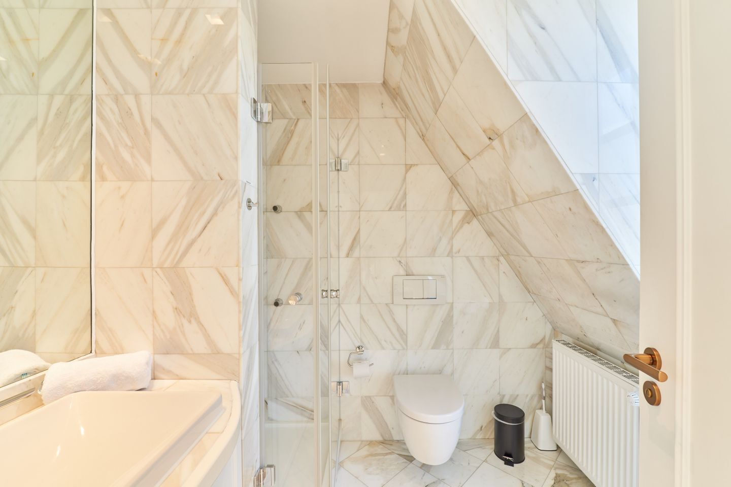 A bathroom with a glass shower enclosure, a white toilet, a radiator, and a bathtub.