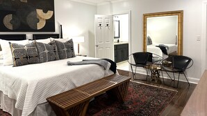 A bedroom with a bed, a ceiling fan, a large mirror, and a wooden bench.