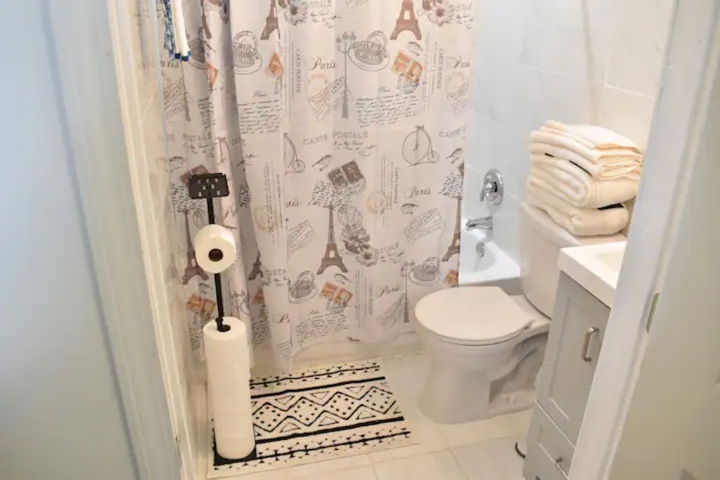 A bathroom with a toilet, a sink, and a shower curtain with Paris-themed designs.