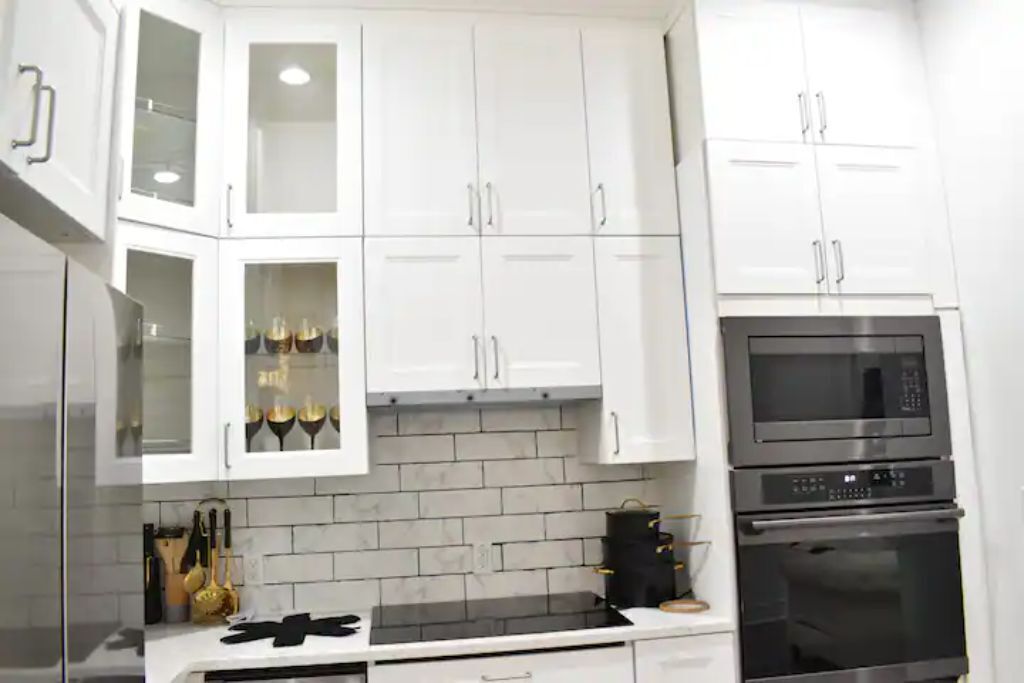 A kitchen with white cabinets, a black stove, and a microwave.