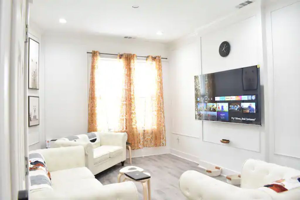 Ein modernes Wohnzimmer mit einer Sofagarnitur, einem Couchtisch und einem an der Wand befestigten Flachbildfernseher.