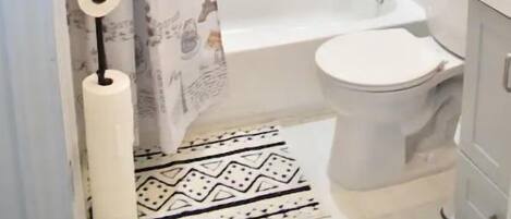 A bathroom with a shower, toilet, and a towel rack.