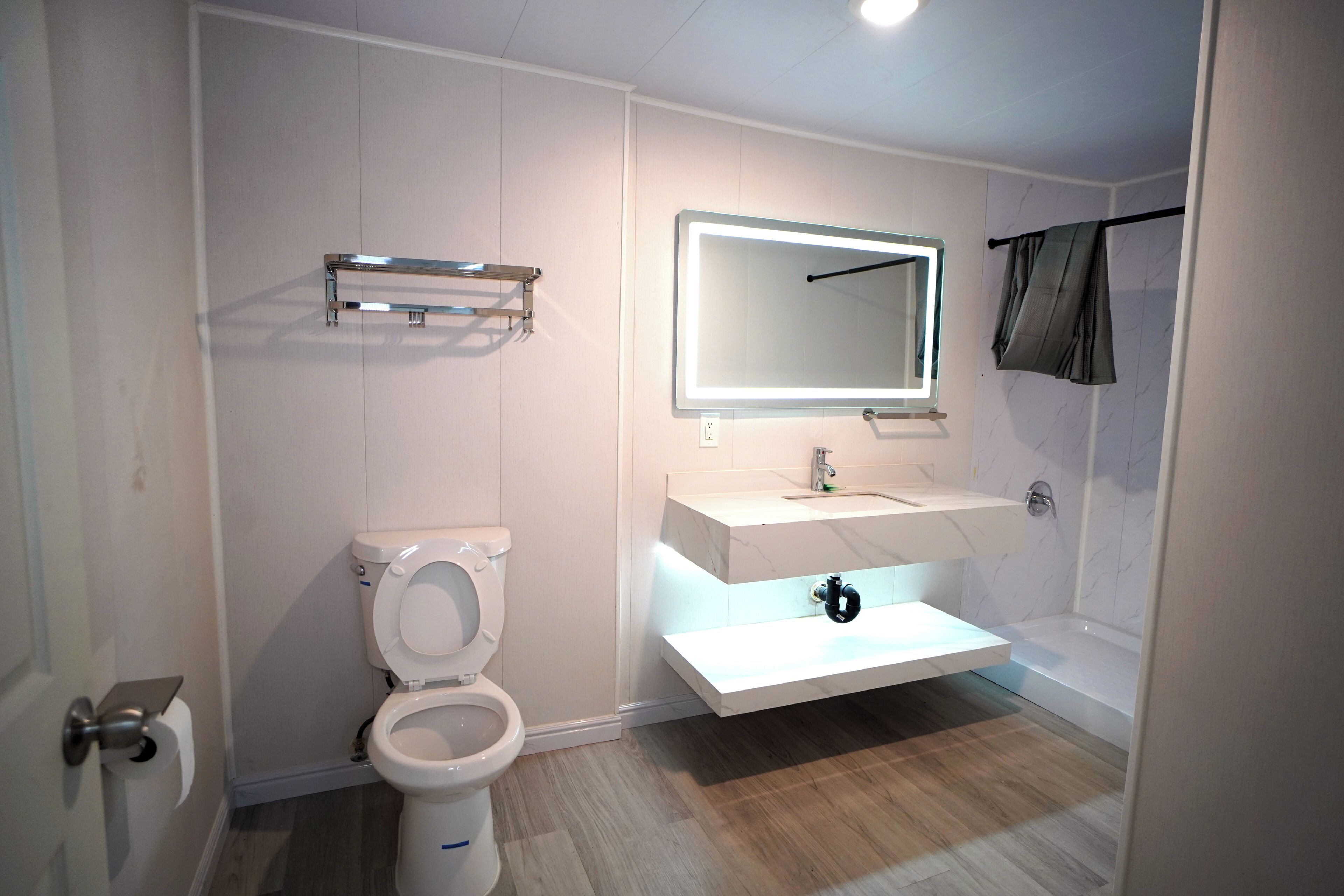 A modern bathroom with a toilet, sink, mirror, and shower. - Airport Stay Motel (Ontario)