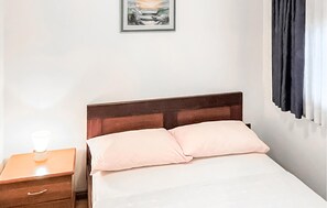A neatly made bed with a wooden headboard, a bedside table with a lamp, and a painting on the wall.