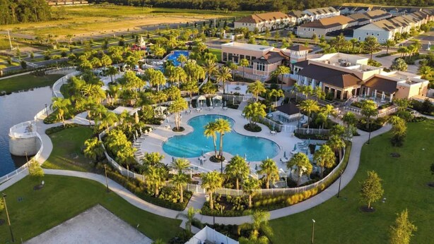 Een resort met een centraal gelegen zwembad, omringd door palmbomen en diverse gebouwen.