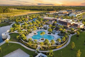 A resort with a central swimming pool, surrounded by palm trees and a variety of buildings. - Luxurious Villa Close to Disney (Kissimmee)